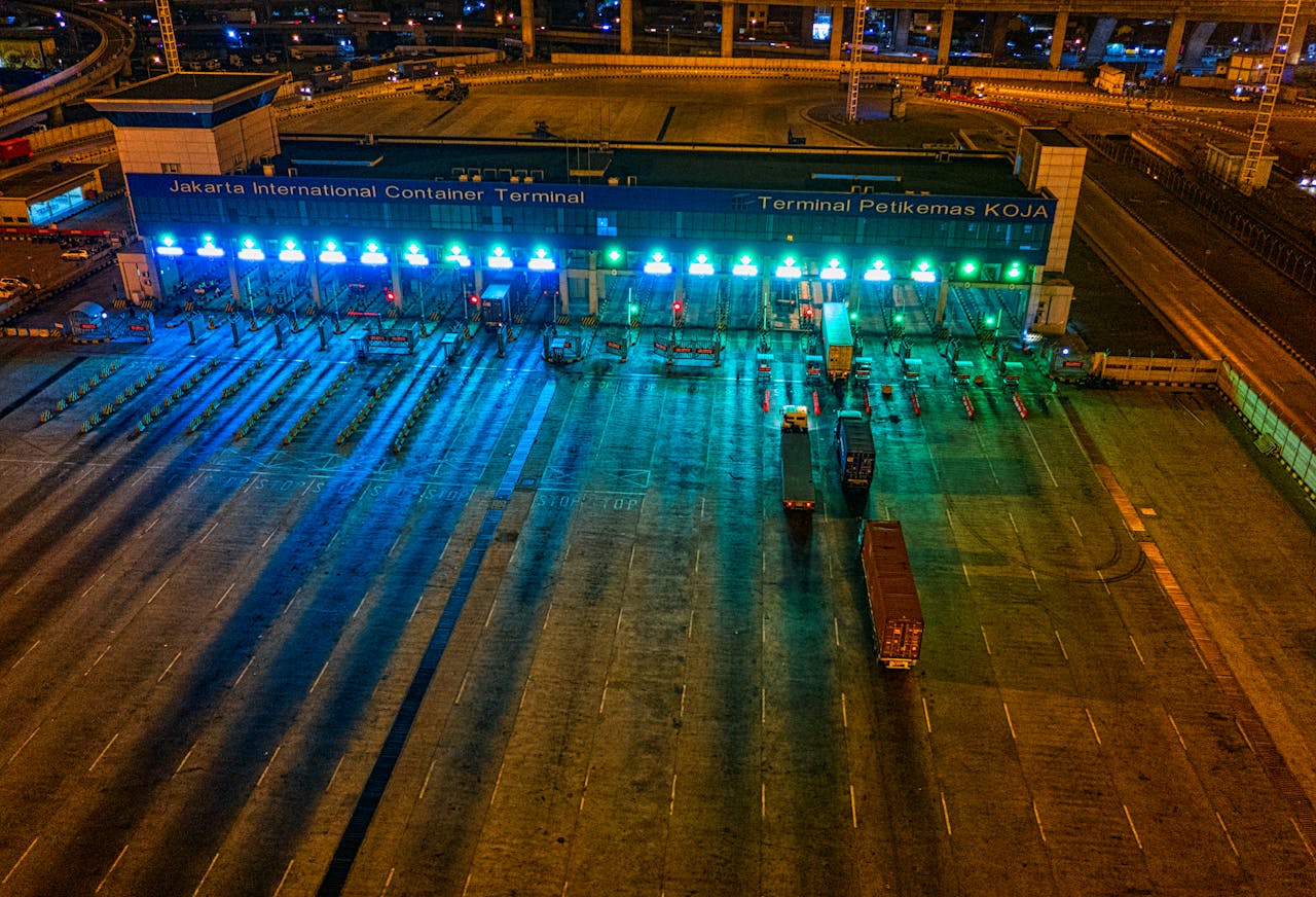 about-us-01 Illuminated aerial view of Jakarta International Container Terminal highlighting logistics activity at night.